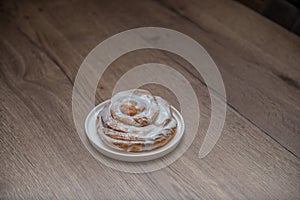 Snail buns on a white plate and wooden background. Cinnamon rolls. Bakery products.