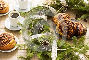 Snail chocolate muffins served with coffee on the background of a wreath of fir branches and cones. Rustic style.