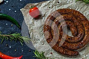 Snail sausage baked in an old oven is on dark background