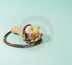 A snake wrapped around an arm containing an apple. The background is blue