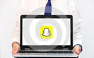 Snapchat Web version concept with laptop screen held by person on white space, editorial background photo