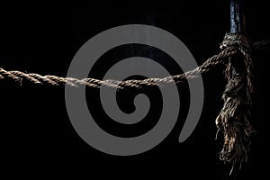 a snapped rope hanging against a black background