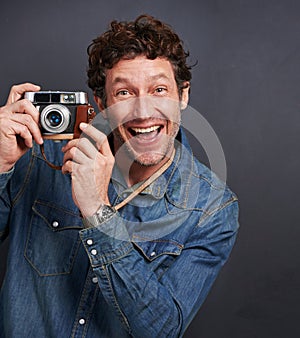 Snappy happy with his camera. Studio portrait of a handsome man posing with his vintage camera and looking excited.