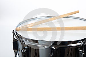 A snare drum with drumsticks on white background