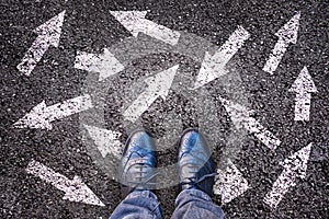 Sneaker shoes and arrows pointing in different directions on asphalt, choice concept photo