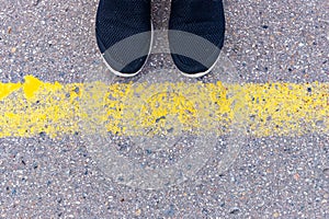 Sneakers on asphalt road with yellow line road marking, top view