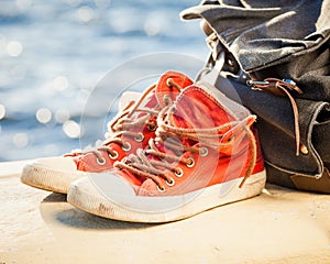 Sneakers and backpack on seascape