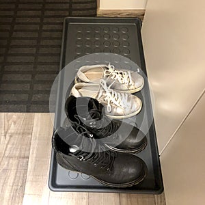 sneakers and boots stand on a shoe tray in the hallway photo