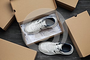 Sneakers and cardboard shoe boxes on wooden floor, flat lay