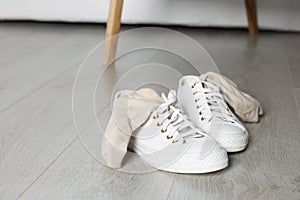 Sneakers with dirty socks on white wooden floor indoors