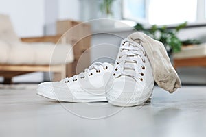 Sneakers with dirty socks on white wooden floor indoors