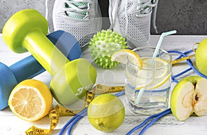 Sneakers,  dumbbell, glass of water with lemon, measuring tape, jump rope, ball,  lime, green Apple, on a gray