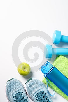 Sneakers, dumbbells, green apple and bottle of water isolated on white background.