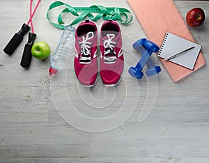 Sneakers dumbbells headphones bottle of water apple and skipping rope