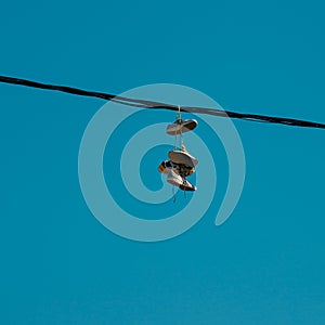 Sneakers hanging on a sky background. The concept of urban culture, sale of prohibited substances, ghetto