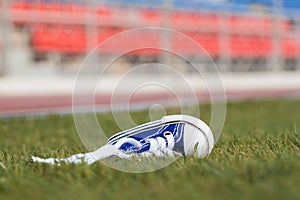 Sneakers lying on a football field. Concept of losing, tired, defeated, fall, pain