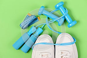 Sneakers with skipping rope and tape on green background.