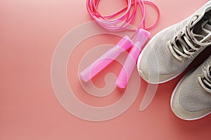 Sneakers, sport shoes and jumping rope over pink background. Health, running workout, fitness and yoga concept. Feminine