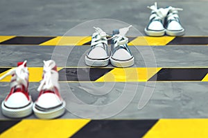 Sneakers and warning tape on the asphalt background.