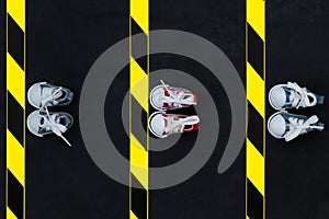 Sneakers and warning tape on the asphalt background