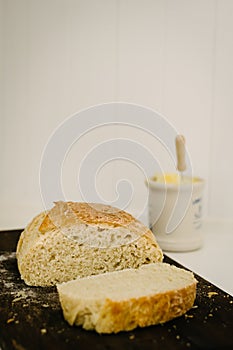 Sneaky Sourdough, homemade, on a breadboard with butter pot