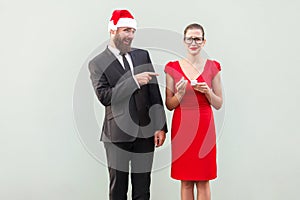 Sneer and mock concept. Man pointing fingers at woman and smiling. Woman crying and holding bad gift