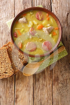 Snert Split Pea Soup with vegetables,  smoked sausages and pork closeup in the plate. vertical top view