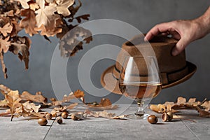 Snifter of brandy on a stone table with dried-up oak leaves