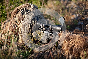 Sniper in ghillie suit with precision rifle with optic sight