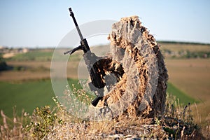 Sniper in ghillie suit with precision rifle with optic sight