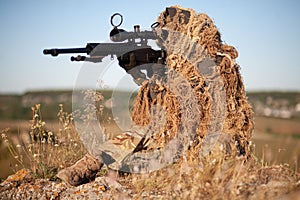 Sniper in ghillie suit with precision rifle with optic sight