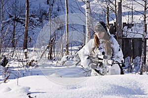 Sniper girl in white camouflage at winter forest.