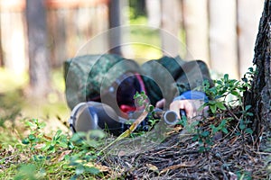 Sniper with paintball gun disguised in grass. Focus on top of ba photo