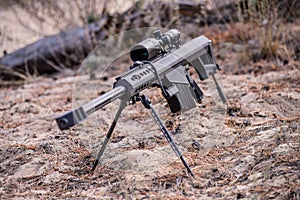 Sniper rifle on bipod with scope on ground background