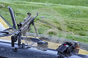 Sniper rifle, laser rangefinder, ammunition and metal cup on a dirty hood of offroad vehicle. Hunting concept