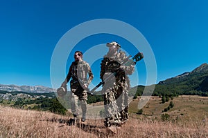 A sniper team squad of soldiers is going undercover. Sniper assistant and team leader walking and aiming in nature with