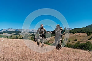 A sniper team squad of soldiers is going undercover. Sniper assistant and team leader walking and aiming in nature with