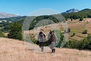 A sniper team squad of soldiers is going undercover. Sniper assistant and team leader walking and aiming in nature with