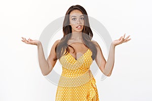 Snobbish unsure and arrogant brunette woman in yellow dress look with disdain and fatigue, tired of picking between two photo