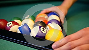 Snooker or billiard. In a billiard club or a night club a man puts billiard balls on a pool table, game is going to begin