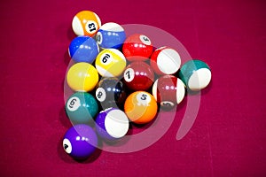 Snooker multicolored balls lay as a pyramid on the table. Closeup view. Billiard red table with cue and balls. Leisure, hobby,