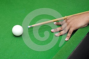 Snooker player with billiard cue ready to hit white ball with selective focus
