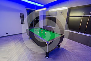 Snooker Pool Billiards room, green table with complete set of balls in a modern room with neon lights