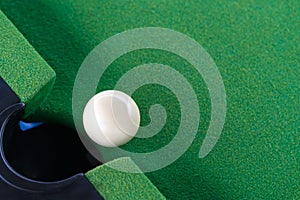 Snooker white ball near the hole on green snooker table