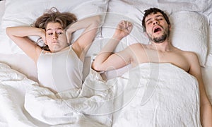 Snoring concept. Young woman is covering her ears. Man is snoring in bed