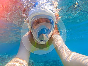 Snorkel girl underwater selfie. Snorkeling in full face mask. Summer activity.