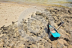 Snorkel, mask, fins and simple spear fishing harpoon on sun lit rocky beach near sea, local Malagasy fisher equipment