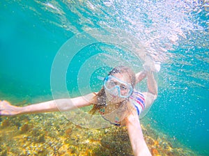 Snorkeling blond kid girl underwater goggles and swimsuit