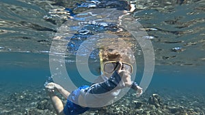 Snorkeling child diving in clear blue ocean water with beautiful colorful fishes