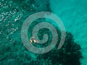 Snorkeling couple in the middle of the Indian Ocean, coral reefs, green water, from high above. Birds eye view.